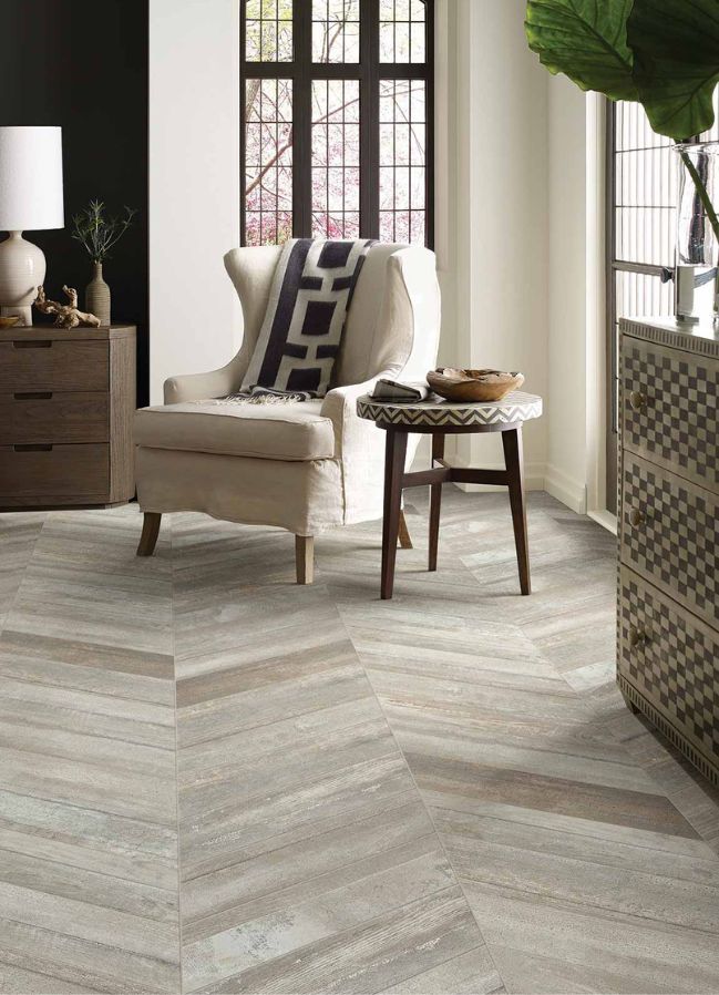 wood look tile flooring in a bright living room with upholstered chair and large corner windows