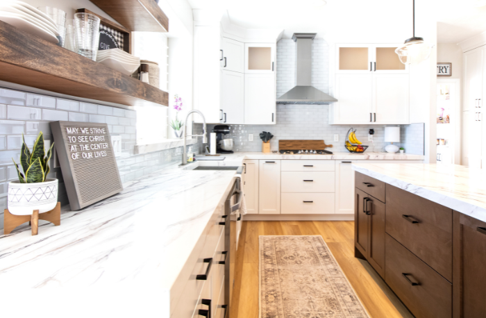 Image Alt Textbrown and white cabinets with white ston countertops in kitchen with subway tile backsplash and wood look flooring